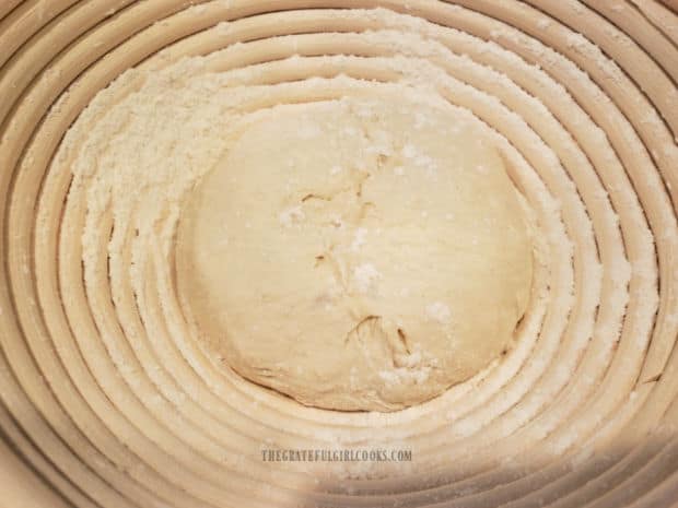 Bread dough ball is transferred top side down into a floured banneton basket for rising.