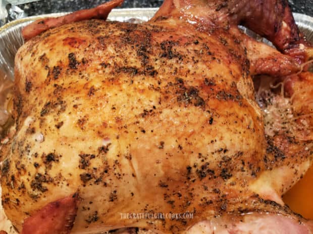 Smoked whole turkey rests after being removed from grill, before slicing.