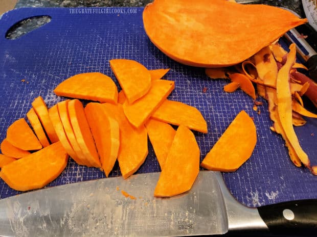 A large sweet potato is peeled, halved, then cut into moon shaped slices.