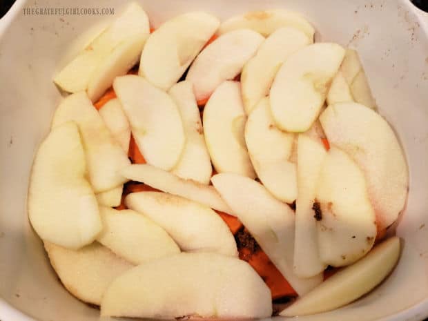A baking dish with bottom layer of sweet potato and brown sugar, topped with apple slices.