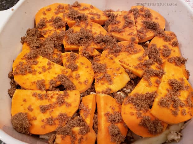 Brown sugar is sprinkled on final layer of sweet potato slices in baking dish.