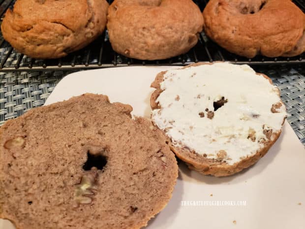 A bagel, cut in half and smeared with cream cheese, ready to be eaten.