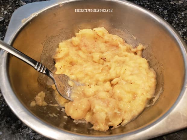 Bananas are mashed with a fork before adding them to the bagel dough.