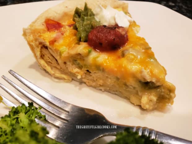 A white plate with a piece of the chicken enchilada quiche, ready to be devoured.