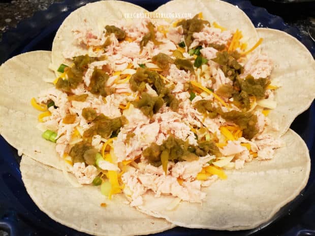 Shredded chicken, chilis, and cheeses are placed in the tortilla crust.