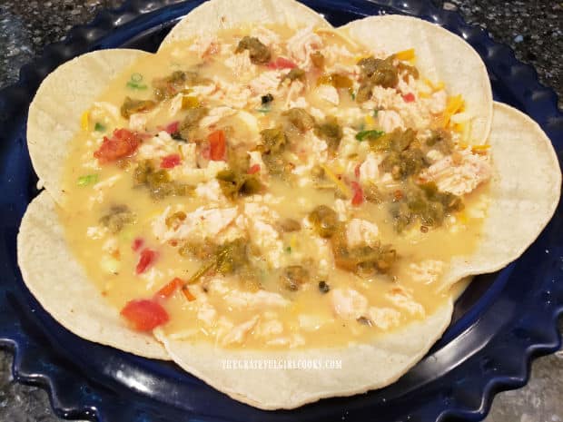 Egg mixture has been added to the chicken enchilada quiche in a pie pan.