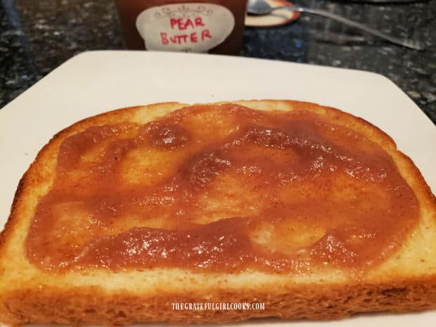 A piece of toast with some of the homemade pear butter spread on it.