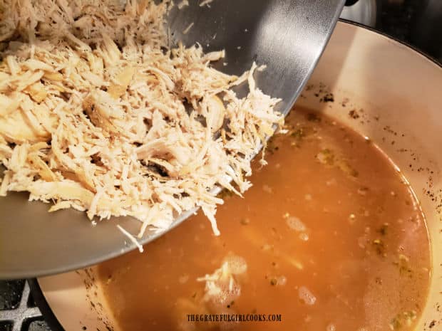 After cooking through, chicken is removed, shredded, and then added back into soup.