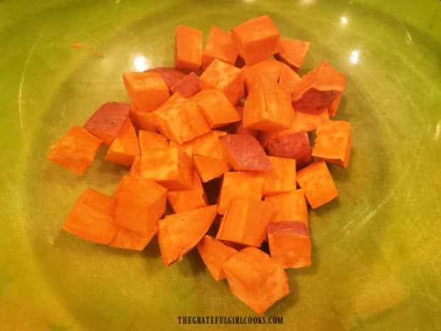 Diced sweet potatoes in a large glass bowl, ready for seasoning.