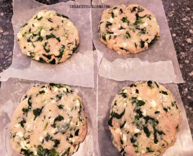 Four turkey, feta and spinach burgers are shaped into patties and placed on waxed paper.