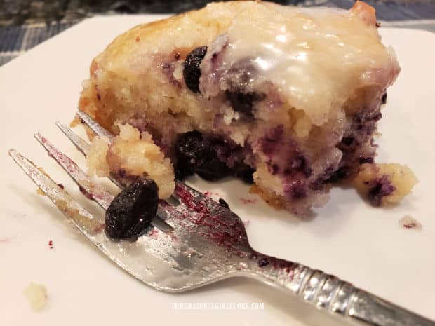 A fork and one of the vanilla glazed blueberry biscuits, on a white plate.
