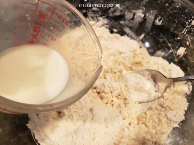 Buttermilk is slowly drizzled into the dry biscuit mixture.