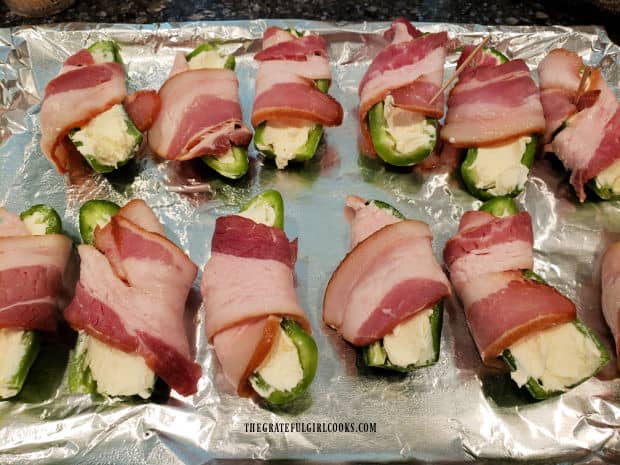 Half a slice of bacon is wrapped around each of the stuffed jalapeños.