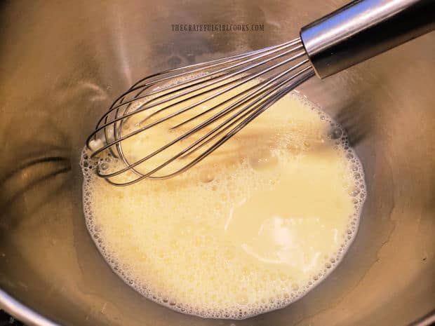 Egg and milk are whisked together in a large mixing bowl.