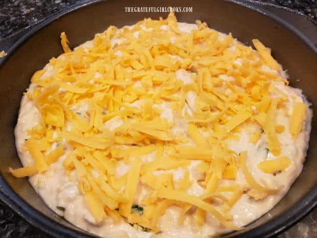 More grated cheese is added to the top of the bread batter in pan.