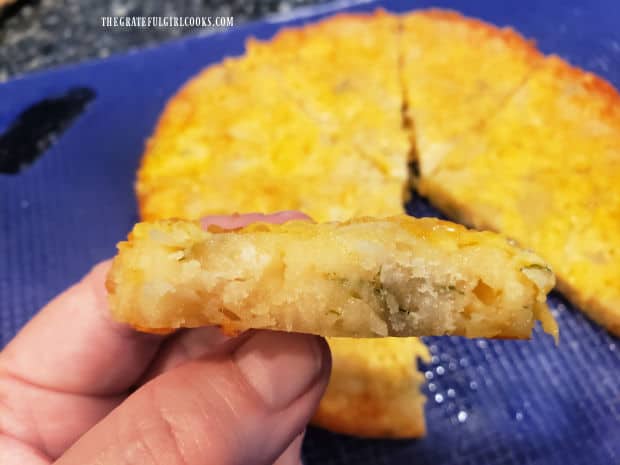 A side view of one of the cheesy bread wedges, showing cheese and parsley inside.