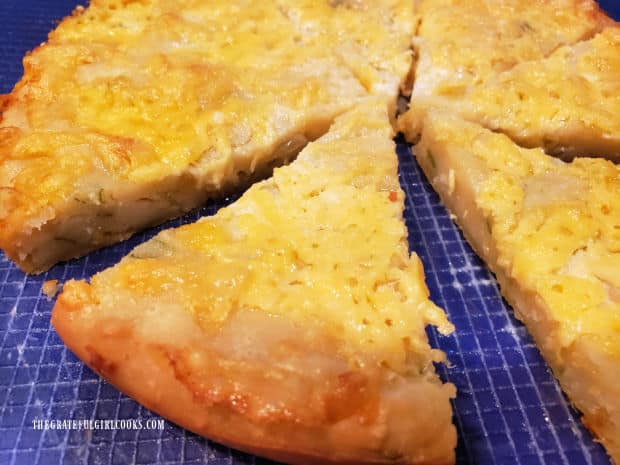 One of the pieces of cheesy bread wedges is sliced, and is ready to eat.