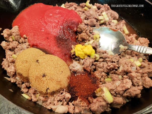 Tomato sauce, brown sugar and other seasonings are added to the browned ground beef in skillet.