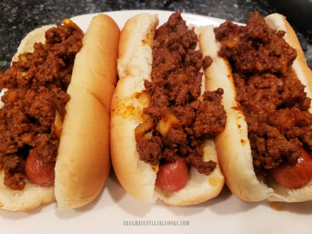 The Coney meat sauce is spooned on top of cooked hot dogs in buns, to serve.