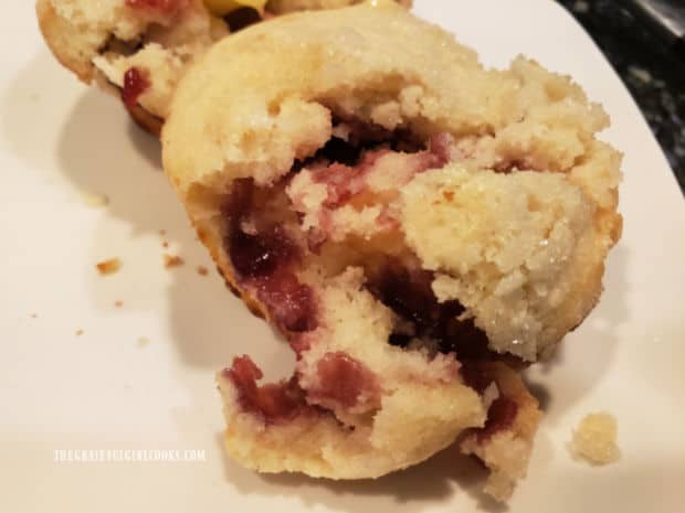 One of the raspberry surprise muffins is cut apart, revealing the surprise filling hidden inside.