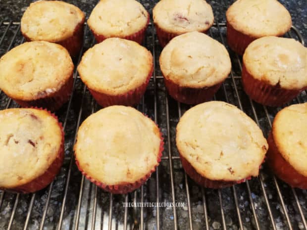 A dozen Raspberry Surprise Muffins cooling on a wire rack after baking.