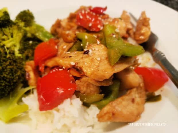 A close up of the rice bed below the serving of Szechuan chicken on a white plate.