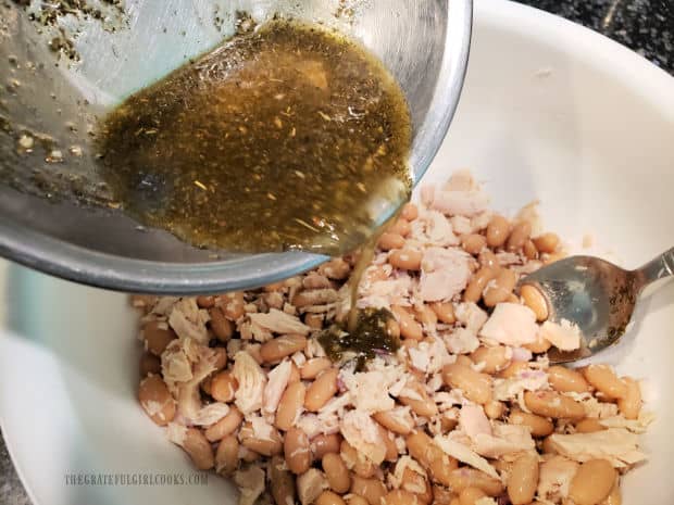 Salad dressing is poured over the Tuscan Cannellini Tuna Salad before mixing.