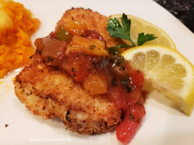 This piece of air fryer crusted mahi mahi is served with fruit salsa on top and lemon on the side.