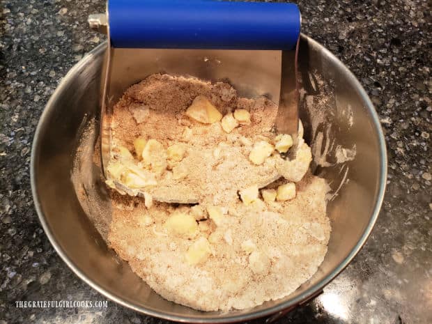 A pastry cutter is used to cut the cold butter into the streusel topping.