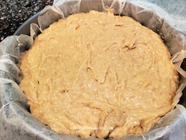 Coffeecake batter is spread into a parchment paper lined cake pan.