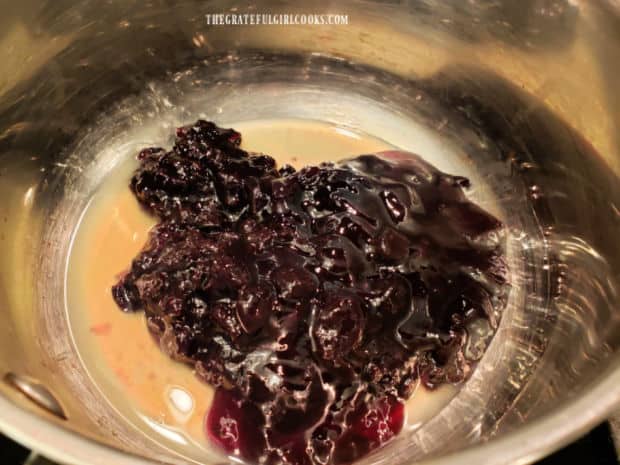 Blueberry jam and lemon juice are warmed in a saucepan on low heat.