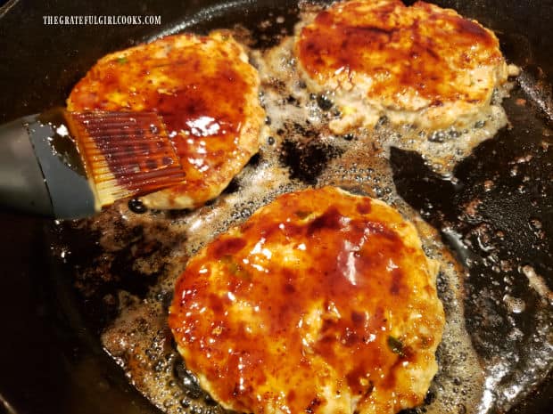 Sauce is brushed onto the top of each of the chicken burger patties.