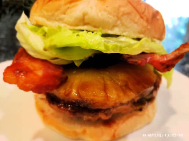 A plate with a chicken pineapple bacon burger on it, ready to be eaten and enjoyed.