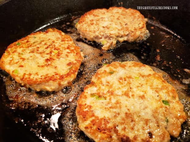 After the bottom of the patties brown, the burgers are flipped over in the skillet.