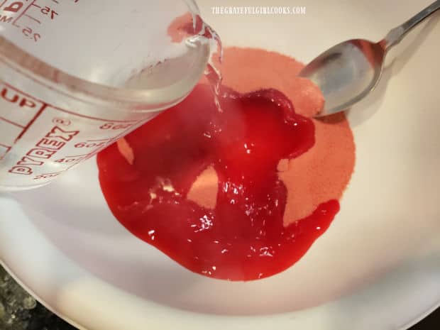 Hot water is stirred into the raspberry gelatin powder and stirred to dissolve powder.