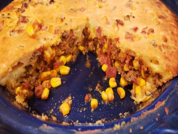 Slices of the tamale pie have been cut and removed, revealing the beef filling inside.