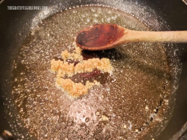 Minced garlic is cooked in melted butter in a large skillet.