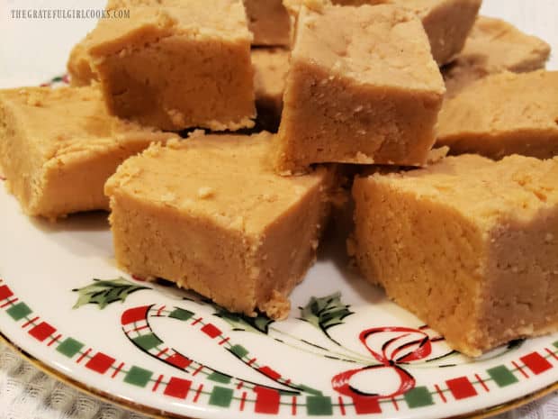 A close up look at a few pieces of the peanut butter fudge on a Christmas plate.