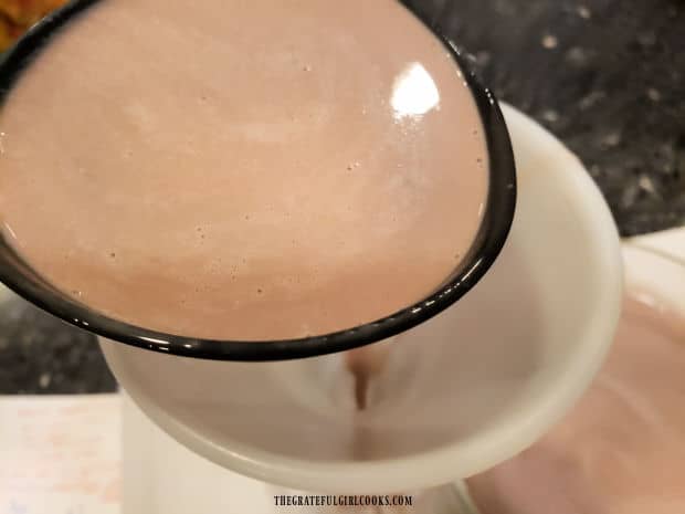 Peppermint Mocha Coffee Creamer is ladled into a funnel on top of a storage bottle.