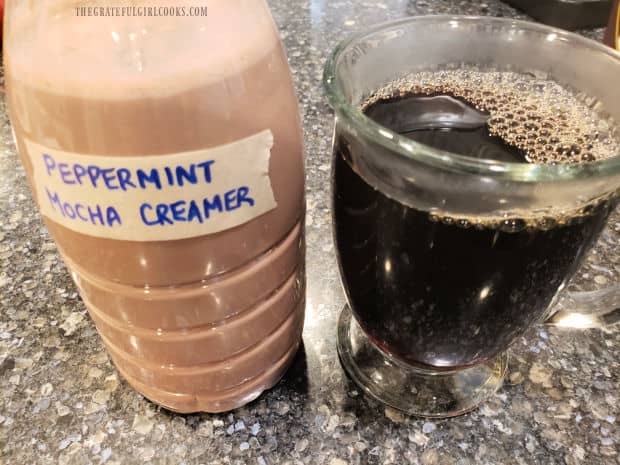 A container of peppermint mocha coffee creamer and a cup of hot, black coffee, ready for creamer.