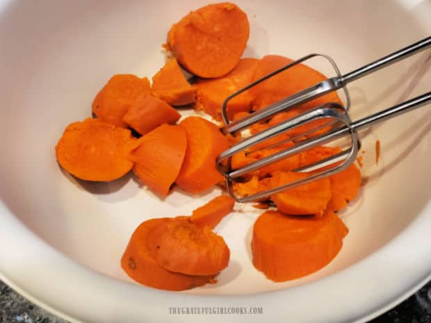 After cooking, sweet potatoes are peeled and then mashed using an electric mixer.