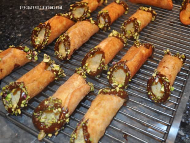 Both ends of cannoli shells are dipped in melted chocolate and sprinkled with chopped pistachios.