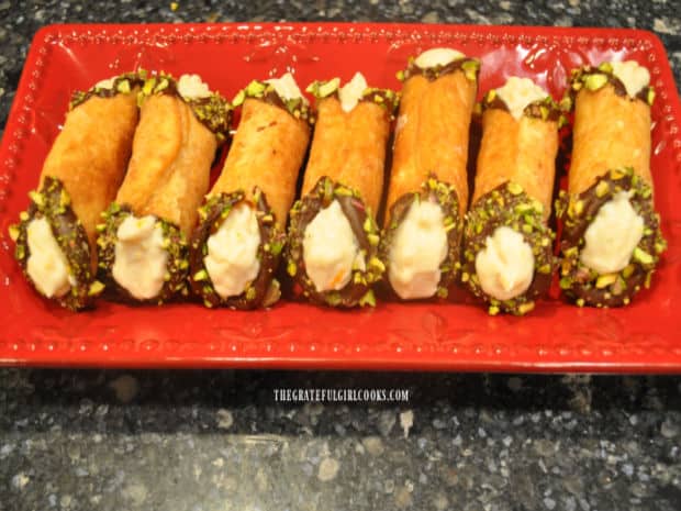 A red serving platter holds seven citrus cannoli that are ready to be eaten!
