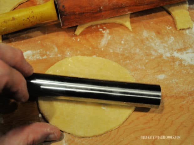 One of the dough circles is wrapped around a metal cannoli tube.