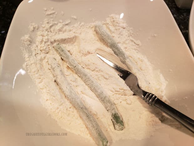 Green beans are dredged in flour mixture to cover.