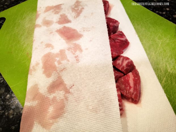 Paper towels are used to absorb excess moisture from the beef bites before searing.