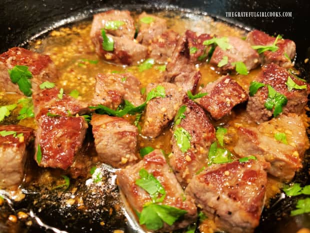 Melted butter, minced garlic, and chopped parsley are added to the steak bites.
