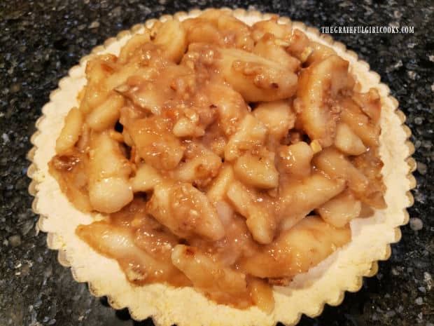 Sliced pear filling is added to the shortbread tart crust in pan.