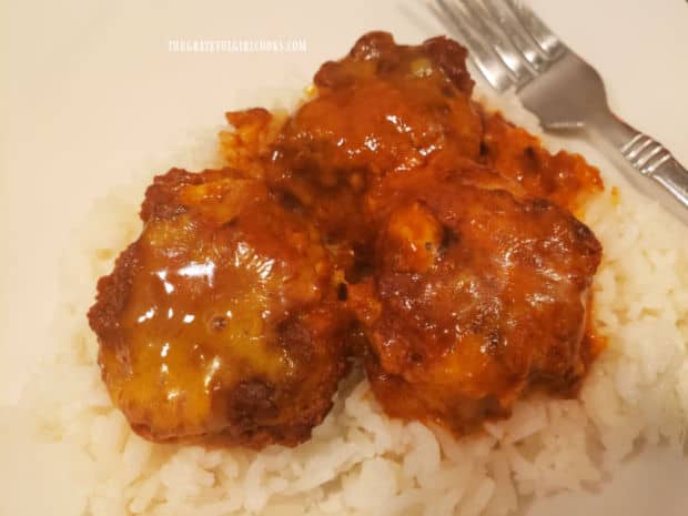 Three of the chicken enchilada meatballs are served hot, on a bed of steamed rice.