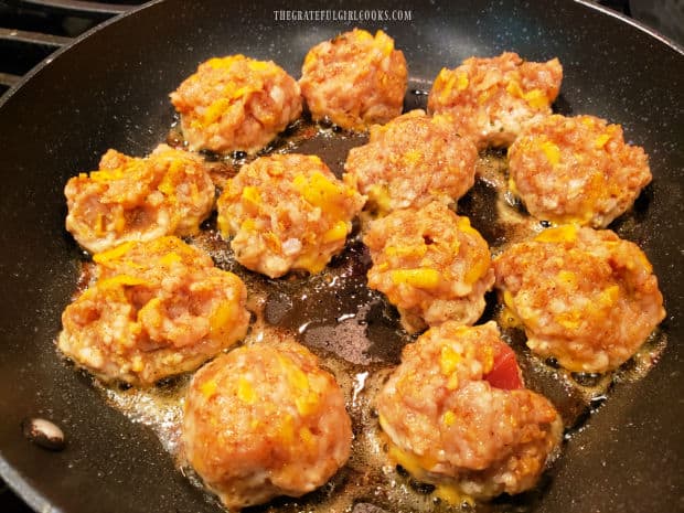 Twelve chicken enchilada meatballs are quickly pan-seared in hot oil in a large skillet.